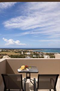 een tafel en stoelen op een balkon met uitzicht op de oceaan bij Panorama Suites in Kastraki Naxou