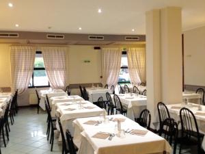 une salle à manger avec des tables et des chaises blanches dans l'établissement Hotel Daina, à Dalmine