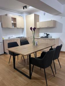 a kitchen with a wooden table with chairs and a vase with flowers at 365 Apartments in Bucharest in Bucharest