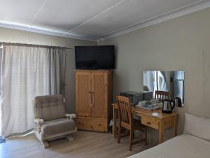 a bedroom with a bed and a desk and a television at Palms Lodge in Kroonstad