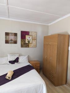 a bedroom with a bed and a wooden cabinet at Palms Lodge in Kroonstad