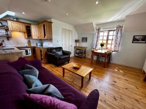 un salon avec un canapé violet et une table dans l'établissement Farm Cottage with wood-fired Hot Tub, à Taynuilt 12 autres photos
