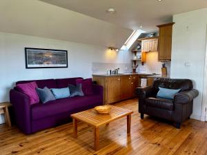 un salon avec un canapé violet et une table dans l'établissement Farm Cottage with wood-fired Hot Tub, à Taynuilt