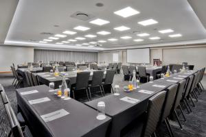 Pretoria的住宿－Protea Hotel by Marriott Pretoria Hatfield，一间会议室,配有桌椅和屏幕