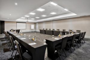 a conference room with tables and chairs and a screen at Protea Hotel by Marriott Pretoria Hatfield in Pretoria