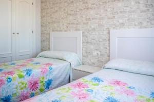 sypialnia z dwoma łóżkami i ceglaną ścianą w obiekcie Casas Rurales Pericón w mieście Conil de la Frontera