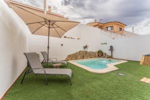 a patio with chairs and an umbrella and a swimming pool at Casa Rural con piscina, Hogar de Zoe in Trujillanos