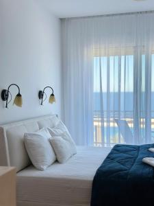 a white bedroom with a bed and a large window at Villa Milan in Sveti Stefan