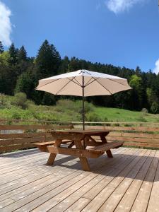 una mesa de picnic de madera con una sombrilla en la cubierta en Gîte pour 4 personnes - Le Grand Valtin, à 2 pas de Xonrupt, en Ban-sur-Meurthe-Clefcy