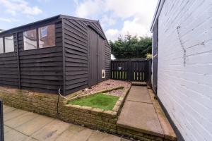 a house with a garden next to a fence at Spacious 3 Bed House, 5mins to HS2/ NEC/Airport. in Marston Green