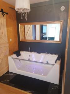 a large white tub in a bathroom with a mirror at 7.Nebo/ Spa apartman Vinkovci in Vinkovci