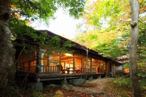 ein Haus im Wald mit Glasfenstern in der Unterkunft Tsuruya Ryokan in Karuizawa