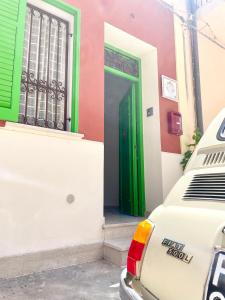 une porte verte sur un bâtiment avec une voiture garée à l'extérieur dans l'établissement Conte125, à Cinisi