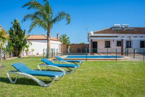 a row of blue lounge chairs in the grass in front of a house at Casas Rurales Pericón in Conil de la Frontera