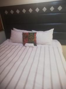 a bed with white pillows and a black headboard at Miami guest house in Vereeniging
