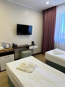 a hotel room with two beds and a flat screen tv at SULO Atyrau Hotel in Atyraū