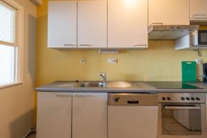 uma cozinha com armários brancos e um lavatório em "Brussel" - Amazing Seaview Apartment in Ostend em Ostend