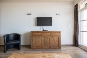 een kamer met een televisie en een zwarte stoel bij "Brussel" - Amazing Seaview Apartment in Ostend in Oostende