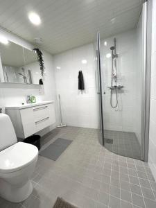 uma casa de banho branca com um chuveiro e um WC. em Scandinavian loft 1BR apartment near city centre em Turku