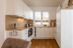 a kitchen with white cabinets and a wooden floor at 5 Sterne Ferienhaus Ostseenest mit Boddenblick in Fuhlendorf