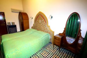 a bedroom with a bed and a dresser and a mirror at Dar El Ghalia in Fez