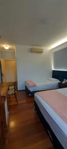 a room with two beds and a table and a chair at Hotel Pousada Minas Gerais in Ouro Preto