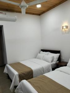 Habitación con 2 camas, paredes blancas y techos de madera. en Jacks Lounge and Hotel, en Kandy