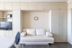 een woonkamer met een witte bank en een tv bij "Sluis" - Cozy Studio with Seaview in Oostende