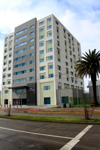 a large white building with a palm tree in front of it at Hotel Diego de Almagro Chillan in Chillán