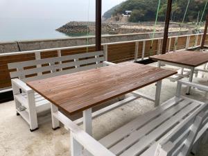 una mesa de madera y bancos en un balcón con vistas en プチリゾート・ひじきwest, en Hijiki