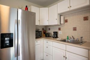 een keuken met witte kasten en een roestvrijstalen koelkast bij C7-Dolphin in St Pete Beach