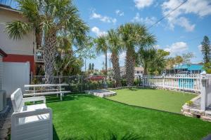 a yard with palm trees and a white fence at C2-Seahorse in St Pete Beach