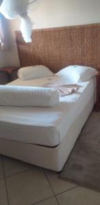 łóżko z białą pościelą i poduszkami w pokoju w obiekcie CFM Sociedade Turística Bilene Resort w mieście Vila Praia Do Bilene