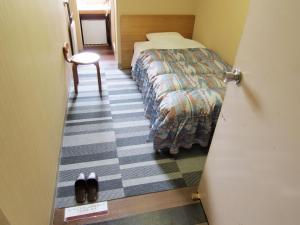 a door to a room with a bed and a chair at Tsukuba Daily Inn in Tsukuba