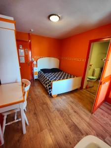 um quarto com paredes cor de laranja e uma cama num quarto em L'Hôtel du Mouton blanc em Fresne-Saint-Mamès