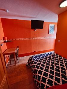 1 dormitorio con 1 cama, escritorio y TV en L'Hôtel du Mouton blanc, en Fresne-Saint-Mamès