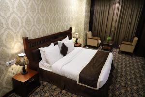 um quarto de hotel com uma cama grande e duas cadeiras em VRC CITY HEART em Bathinda