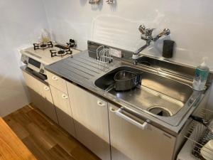 cocina de acero inoxidable con fregadero y fogones en プチリゾート・ひじきwest, en Hijiki