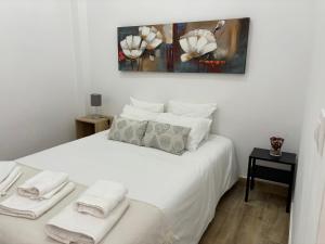 um quarto com uma cama branca e toalhas em Apartamento Cruz Roja A em Sevilha