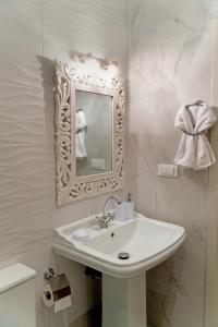 Baño blanco con lavabo y espejo en Carpe Diem Moursia Studio, en Liapades