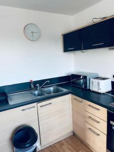 a kitchen with a sink and a clock on the wall at Bally, 2 Bed Flat, by Grays Station in Stifford