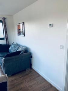 a living room with a green couch and a white wall at Bally, 2 Bed Flat, by Grays Station in Stifford