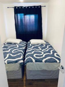 two beds in a room with a blue curtain at Bally, 2 Bed Flat, by Grays Station in Stifford