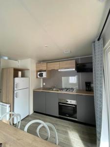 een keuken met een witte koelkast en een tafel en stoelen bij camping des crocs in Saint-Quentin-en-Tourmont