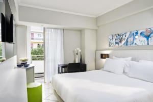 a white bedroom with a large bed and a window at AQUAMARE CITY and BEACH in Rhodes Town