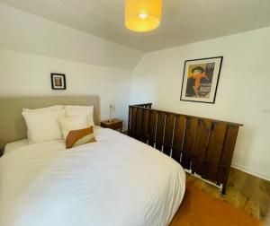 a bedroom with a large white bed with a wooden headboard at The Gate House & Winery in Santenay