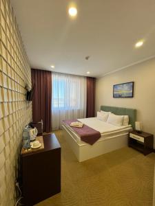 pokój hotelowy z łóżkiem i stołem w obiekcie SULO Atyrau Hotel w mieście Atyrau