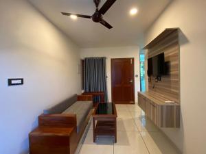 een woonkamer met een bank en een flatscreen-tv bij Grand Residency & Resort in Varkala