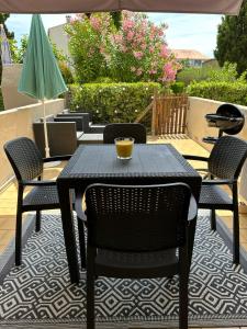 un tavolo nero e sedie su un patio di Le Massilhan - à 100M de la mer a Le Castellas