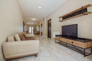 uma sala de estar com um sofá branco e uma televisão de ecrã plano em Villa Lile em Batumi